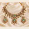 Mint kundan necklace and earrings laid flat on ivory satin