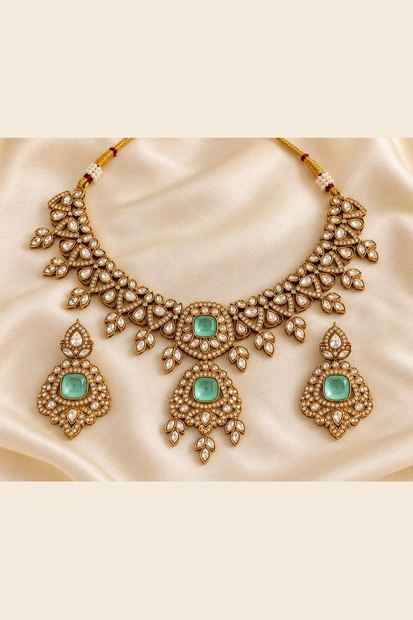 Mint kundan necklace and earrings laid flat on ivory satin