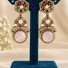 Navratna rose stone earrings on a teal stand, close-up