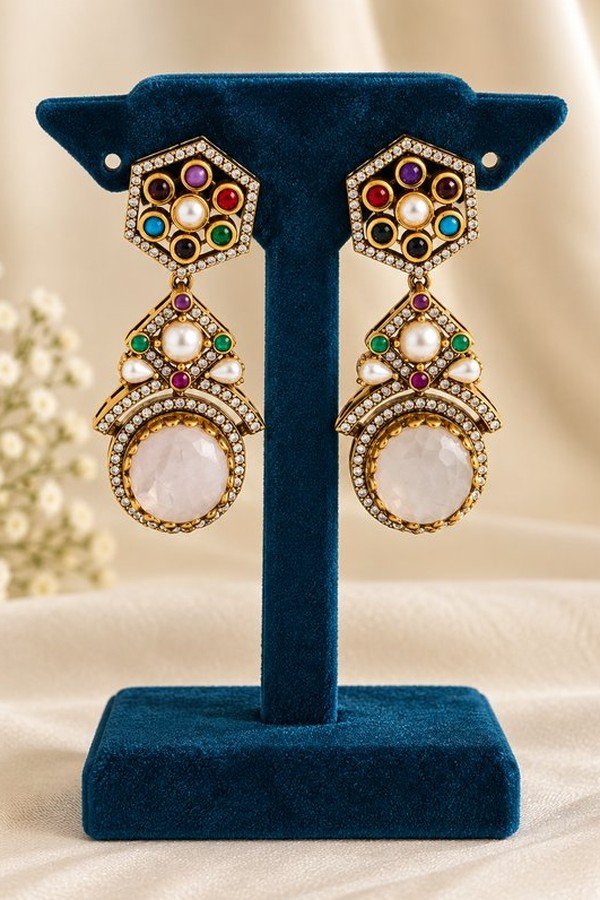 Navratna rose stone earrings on a teal stand, close-up
