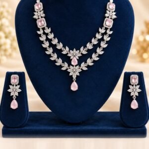Blush pink American diamond two-layer necklace and matching drop earrings on a navy velvet stand