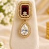 One earring with ruby-toned rectangular stone and clear teardrop drop