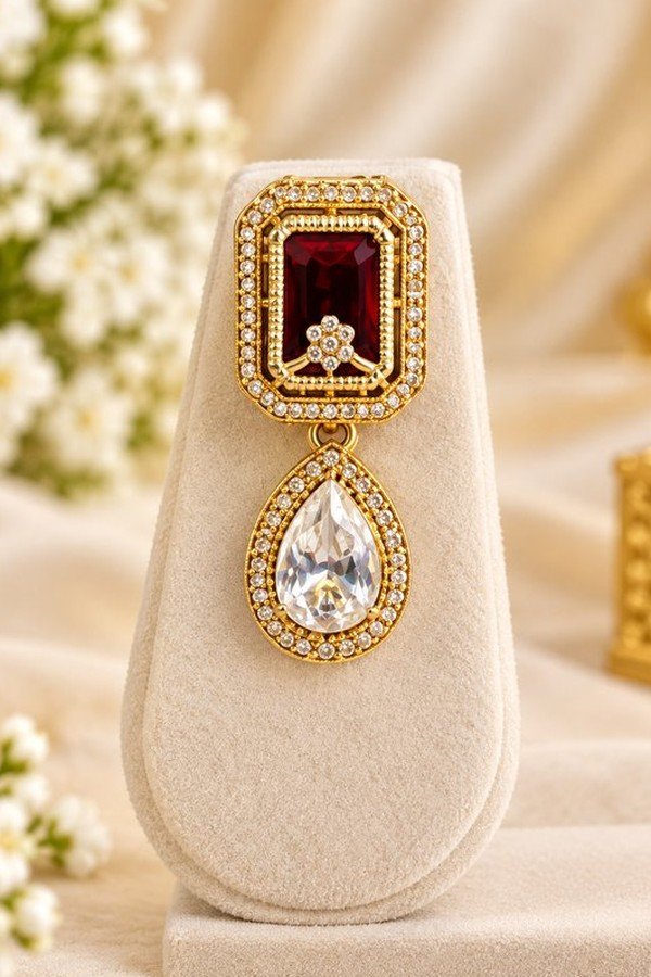 One earring with ruby-toned rectangular stone and clear teardrop drop